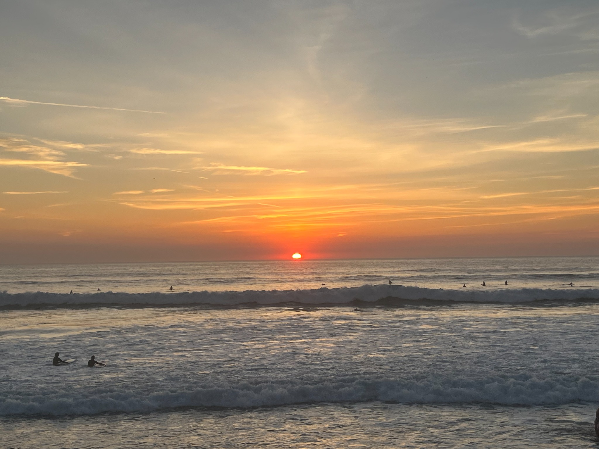 Sunset over the sea with surfers